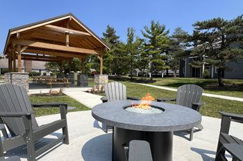 A patio with a fire pit and chairs around it